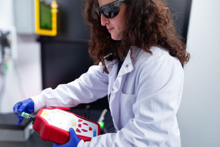 A scientist examining a vaccine vial using a SORS device.